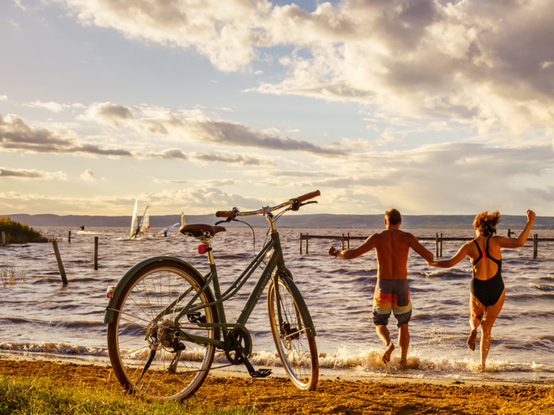 Na bicykli po Rakúsku - Cyklotrasa pri jazerách Rakusko, Neusiedlersee, dvaja cyklisti skacu do jazera