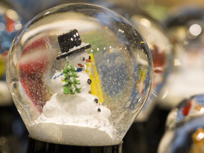 Vieden-snehuliak v sklenenj guli s vianocnycm stromcekom v ruke
